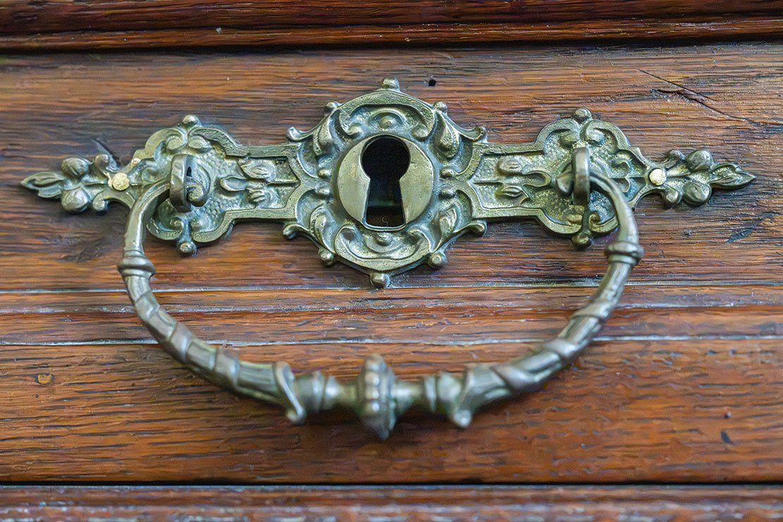 Patinated antique brass hardware with darker recessed details and brighter raised edges